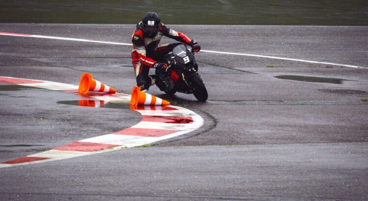 Supermoto rider leaning through a wet asphalt corner around cones