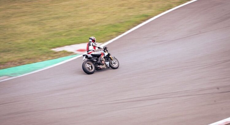 Supermoto rider leaning into a paved track turn near the green edge
