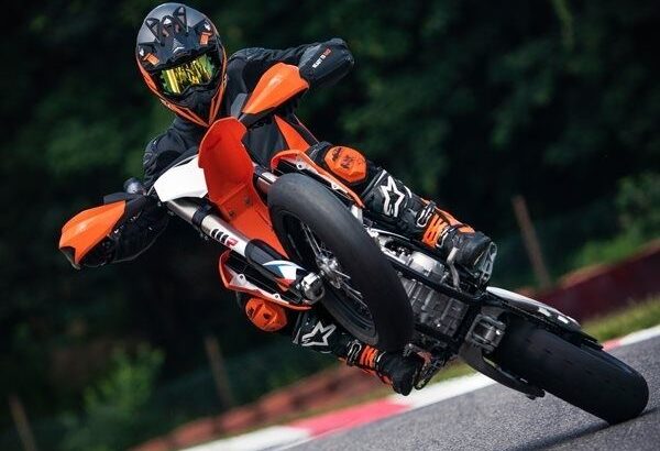 Supermoto rider cornering on asphalt with the front wheel lifted